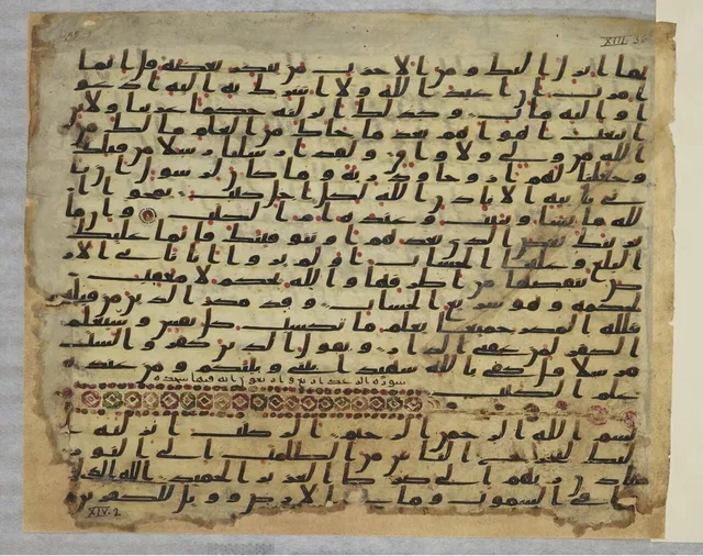 ورقة مصحف بالخط الحجازي، فيها نقط حمراء للحركات وعلامات للآي واسم سورة أُضيف بعد النص (آخر سورة الرعد)